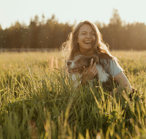 Dog mom and her dog laughing in a sunny field